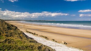 Une plage côtière avec un rivage rocheux et une vue dégagée sur l’océan.