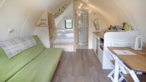 Een compact, goed verlicht interieur met een bed, een kleine kitchenette en een douche.