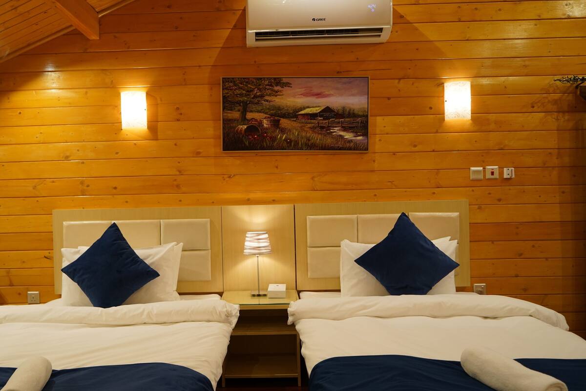 Habitación de cabaña de madera con dos camas, un cuadro y un ventilador de techo.