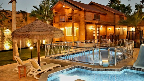 A wooden villa with a pool, lounge chairs, and a thatched umbrella. - The Land Villas Ammaria (Diryah)