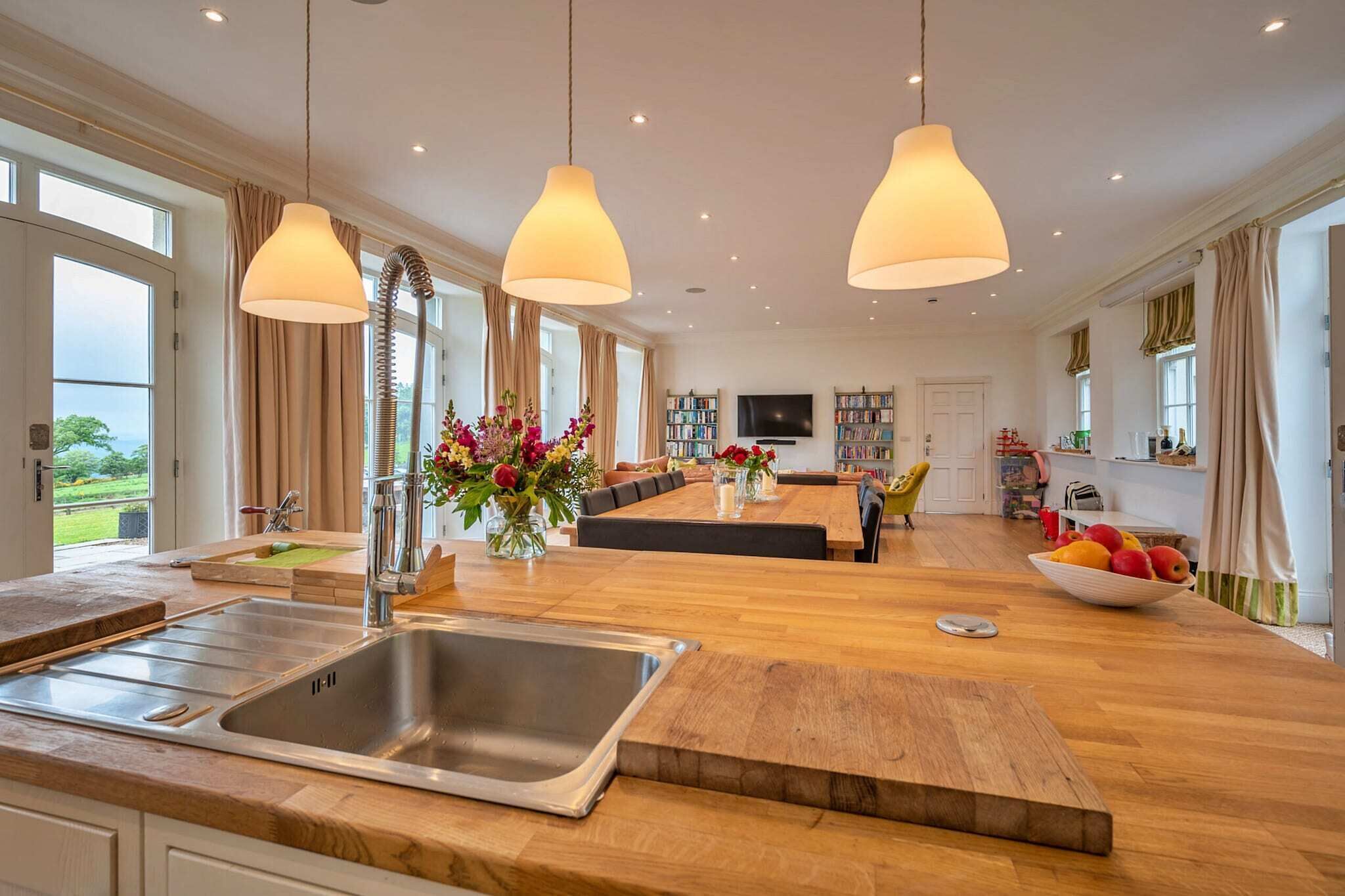 A spacious kitchen with a large island, a dining area with a sofa, and a view of the outdoors.
