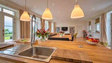 A spacious kitchen with a large island, a dining area with a sofa, and a view of the outdoors.