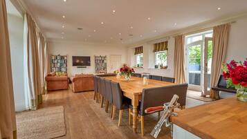 A spacious dining area with a wooden table and chairs, a television, and bookshelves.