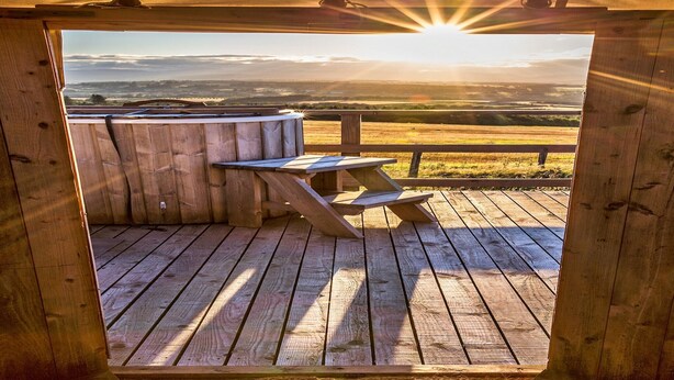 Une terrasse en bois avec une table de pique-nique et une vue sur un paysage.