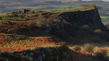 A landscape with a prominent cliff and rolling hills in the background.