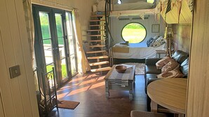 Un interior acogedor con una escalera de madera, un sofá y una mesa de comedor.