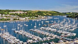 Un puerto deportivo con numerosas embarcaciones amarradas, rodeado por un pueblo con edificios y zonas verdes.