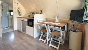 Une cuisine compacte comprenant une table et des chaises, un petit réfrigérateur et un téléviseur fixé au mur.
