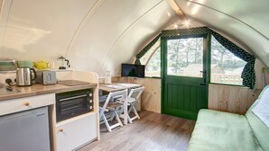 Cocina compacta con refrigerador, estufa y un comedor con sillas.