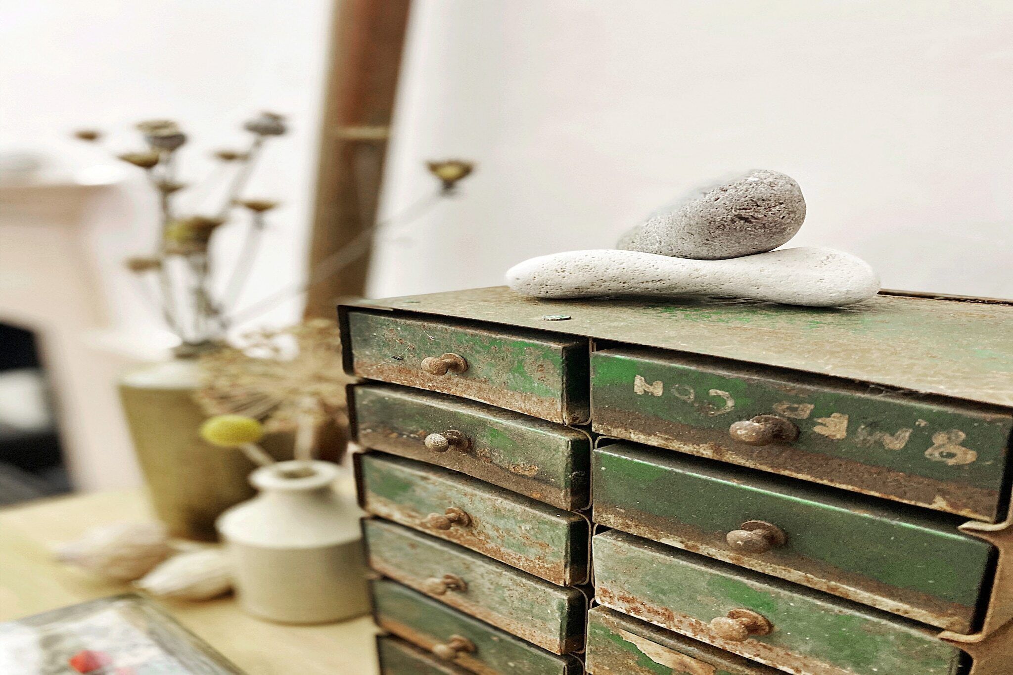 A stack of green metal drawers with a stone on top.