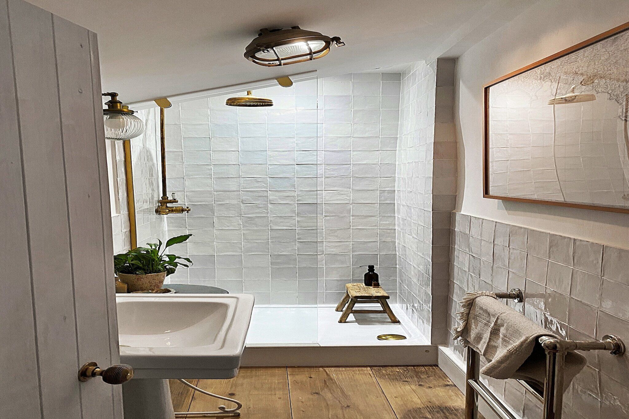 A bathroom with a sink, a small stool, a towel rack, and a framed artwork on the wall.