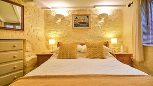 Een slaapkamer met een bed, twee nachtkastjes, een kaptafel, een spiegel en een schilderij aan de muur.