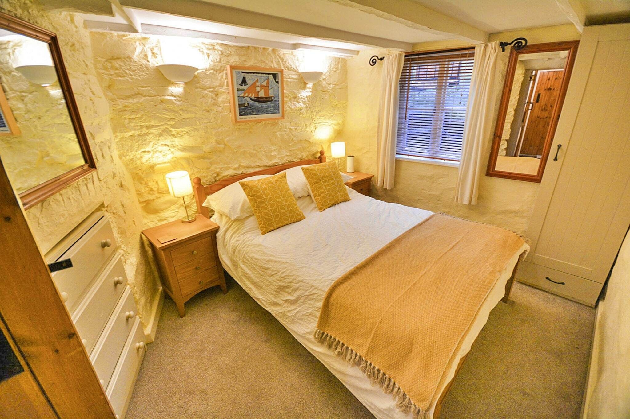 A bedroom with a bed, nightstands, a dresser, a mirror, and a window with curtains.