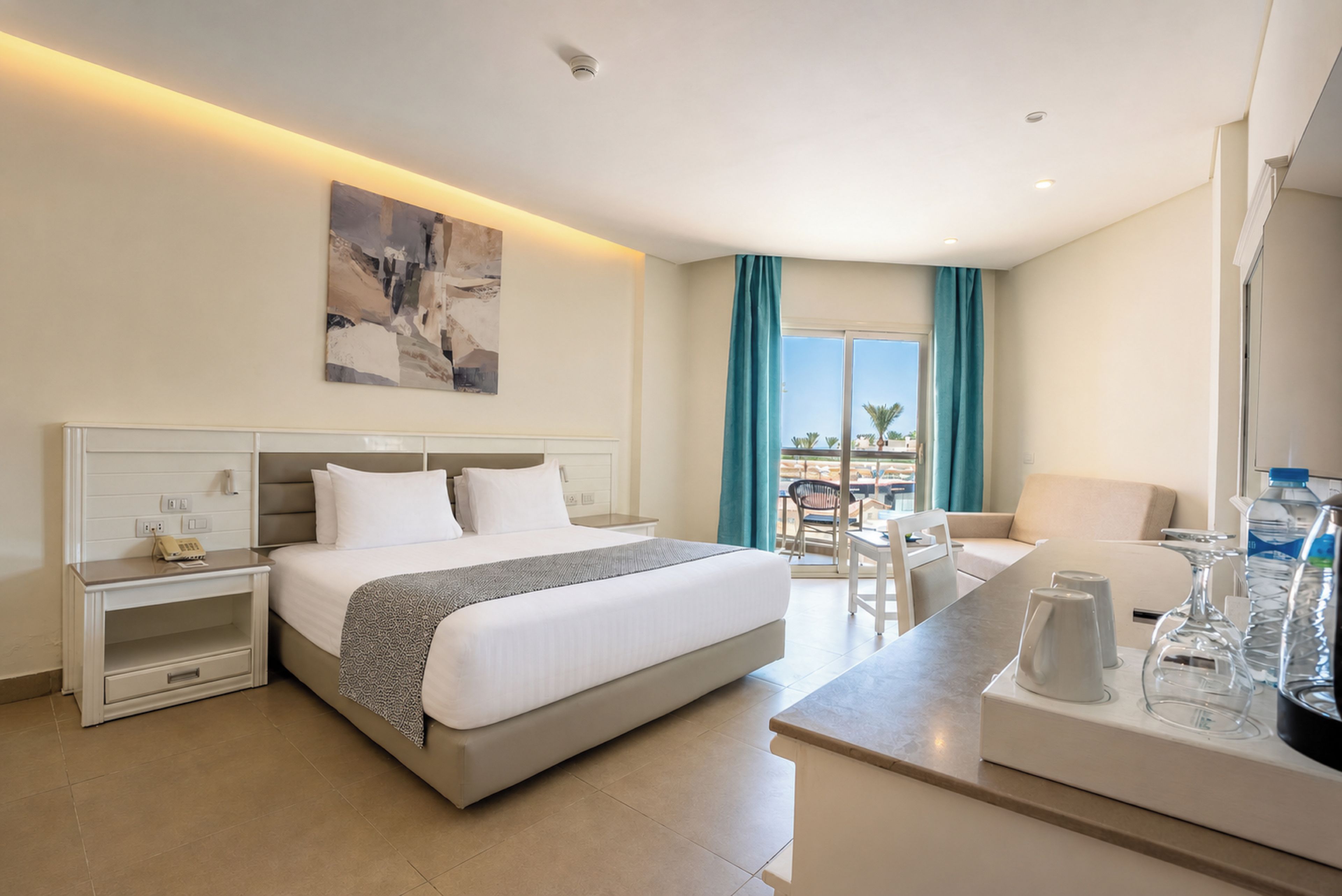 Una habitación de hotel con una cama, mesitas de noche, un escritorio y vistas al exterior.