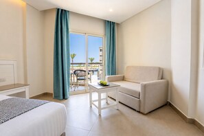 Habitación de hotel con cama, una silla, una mesita y vistas al exterior.