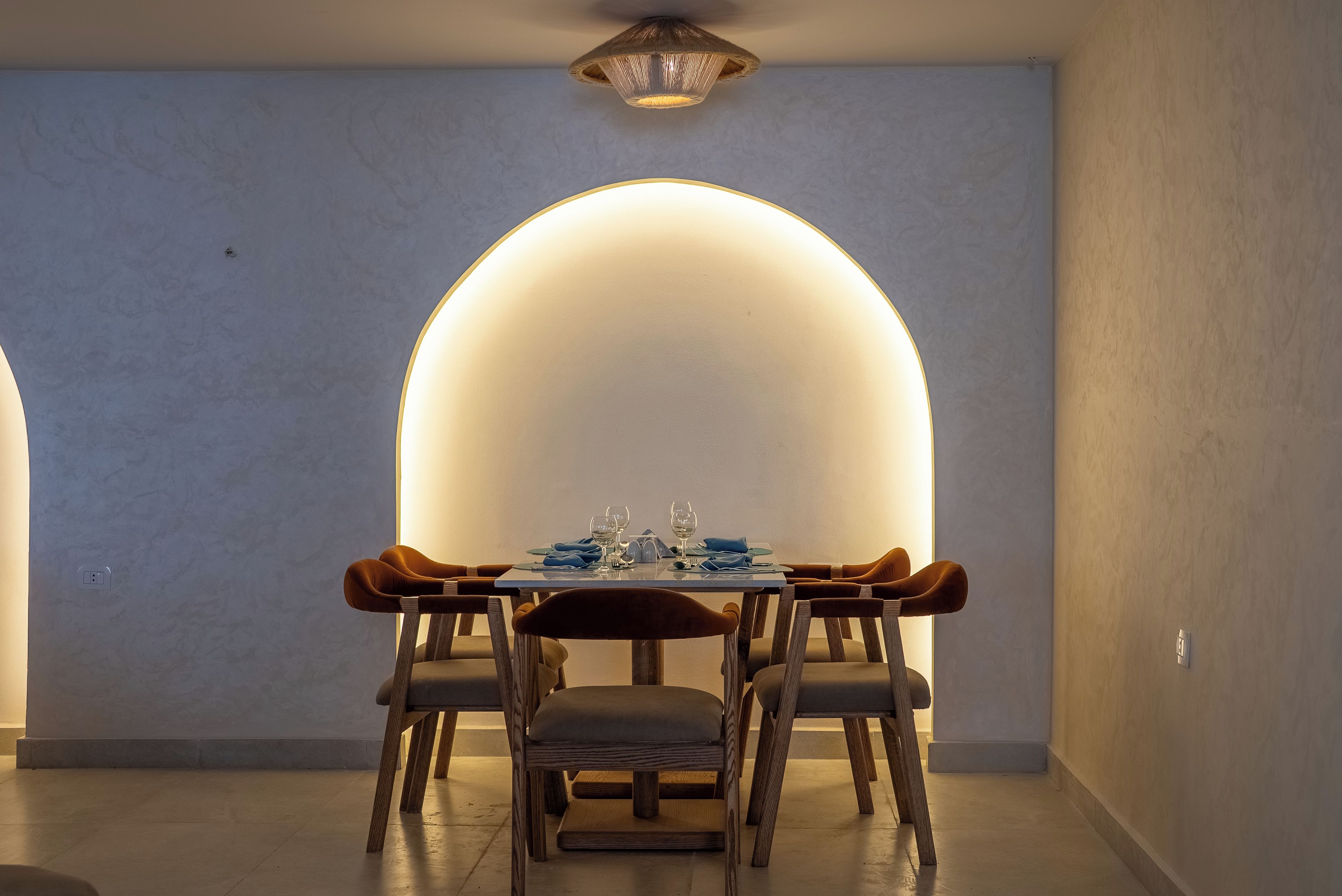 A dining area with a table set for four, surrounded by wooden chairs with cushioned seats.
