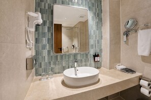 Un baño con un lavabo redondo, un espejo, un perchero para toallas y una zona de ducha.