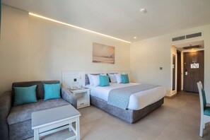 Ein Hotelzimmer mit Bett, Sofa, einem kleinen Tisch und einem Gemälde an der Wand.