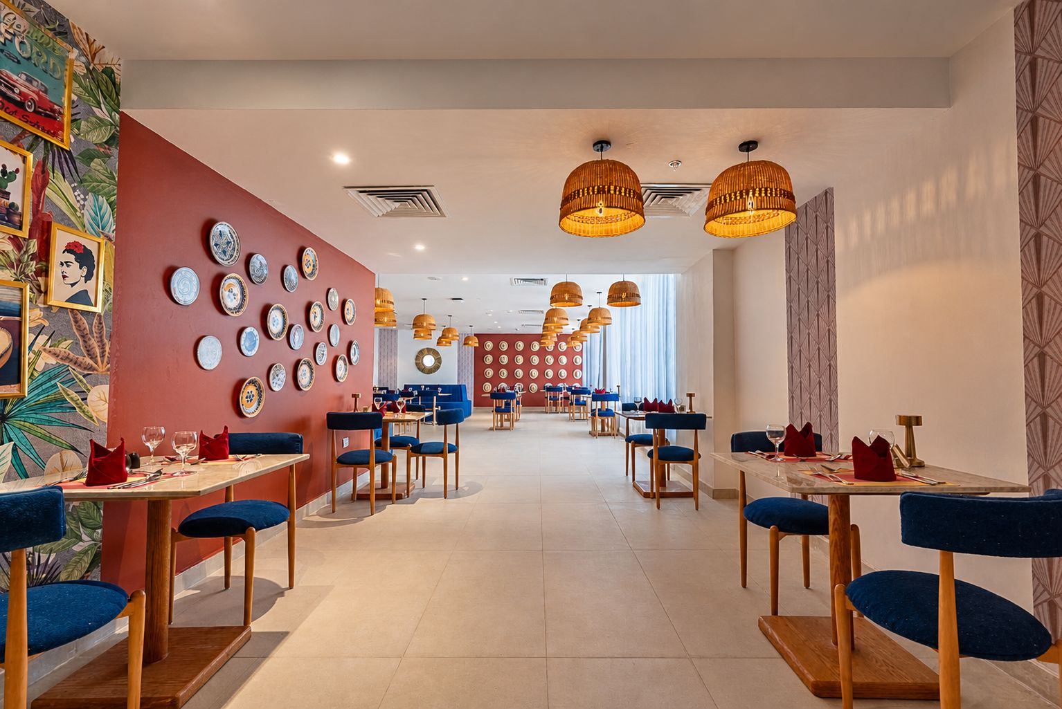 A restaurant with multiple tables and chairs, a patterned wall, and hanging pendant lights.