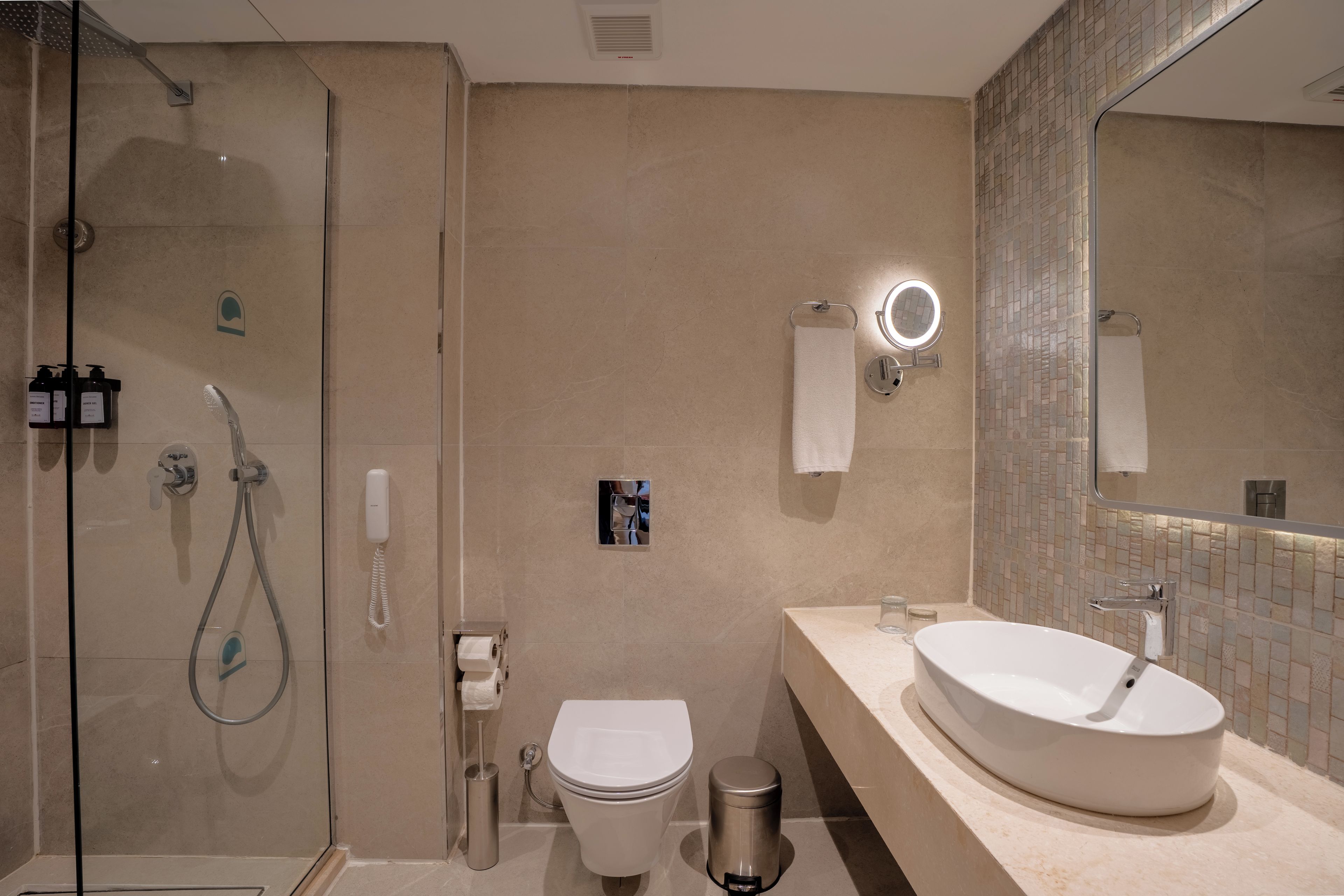 Un baño moderno con cabina de ducha de vidrio, inodoro, bidé, lavamanos con espejo y toallero.