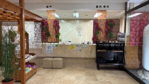 A reception area with a wooden counter, potted plants, and a decorative wall. - Churana Resort Motobu (Motobu)