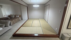 A room with a tatami mat floor, a bed with a headboard, a sofa, and a small table. - Churana Resort Motobu (Motobu)