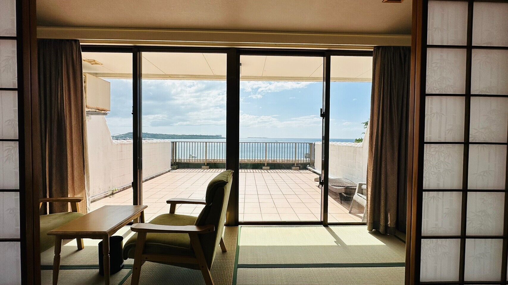 Et værelse med en skydedør, der fører ud til en balkon med havudsigt.