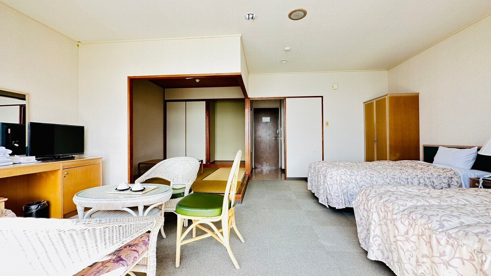 Habitación de hotel con cama, escritorio con televisor, mesa de comedor con sillas y armario.