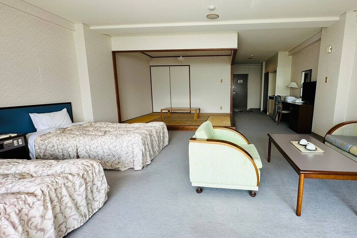 A hotel room with two beds, a sofa, a small table, and a television.