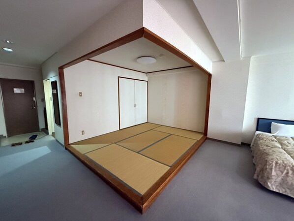 Una habitación con suelo de tatami, una cama con cabecera azul y un armario con puertas correderas.