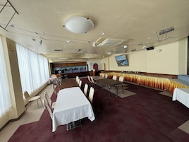 Una sala de conferencias con una mesa larga, sillas, una zona de buffet y una cocina al fondo.
