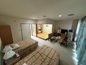 Quarto de hotel com duas camas, uma pequena escrivaninha, uma cadeira, televisão e micro-ondas.