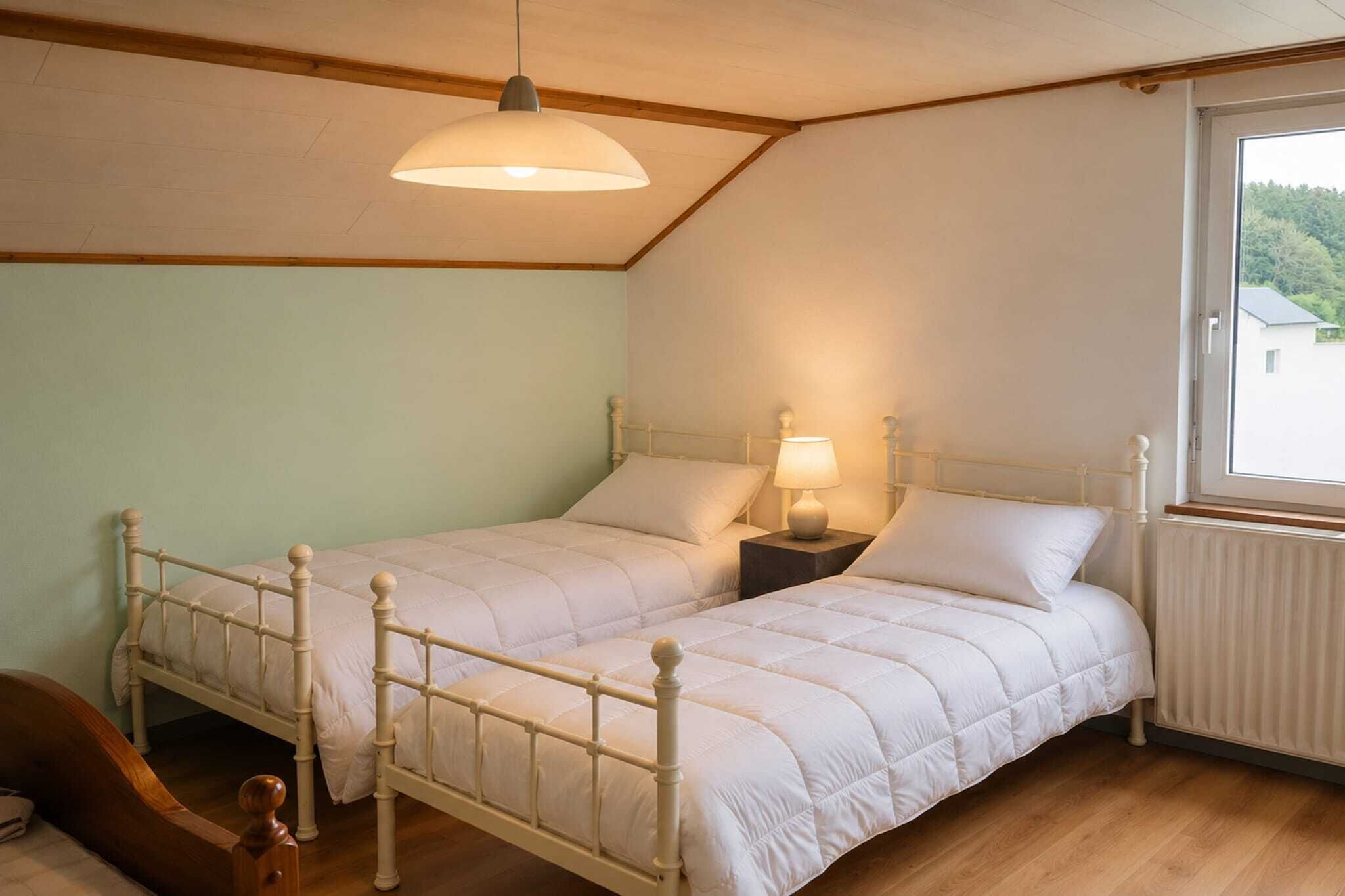 A bedroom with two beds, a wooden ceiling, a window with a view, and a hanging light fixture.