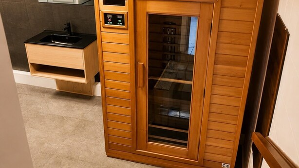 En sauna med træfacade, kontrolpanel og glasdør.
