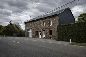 Un bâtiment en pierre avec un toit en pente, une grande porte et de nombreuses fenêtres.