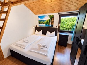 A bedroom with a bed, a painting, a desk, and a wardrobe.