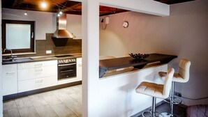 A modern kitchen with a built-in oven, a sink, and a bar area with two bar stools.