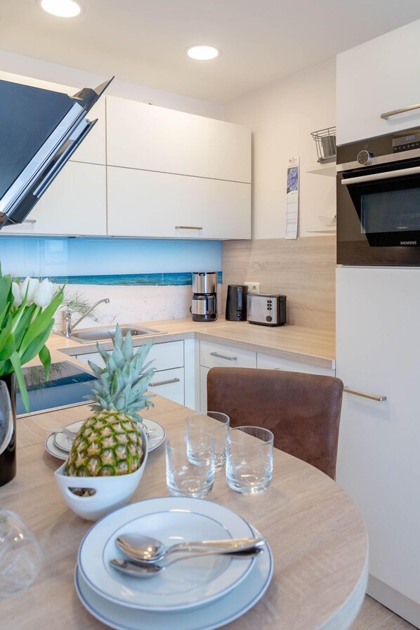 A modern kitchen with white cabinets, a stainless steel oven, and a countertop with a coffee maker and toaster.