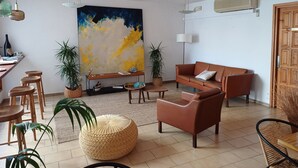 Ein Wohnzimmer mit einem großen abstrakten Gemälde, einem braunen Ledersofa, einem Holztisch und einem Essbereich mit Holztisch und Stühlen.