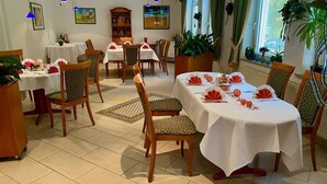 Un espace repas avec des tables rondes, des chaises et des éléments décoratifs, comme des compositions florales.