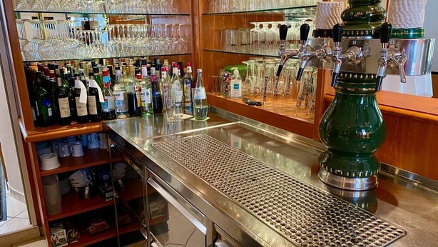 Un espace bar avec un assortiment de bouteilles, de verres et un appareil à café.