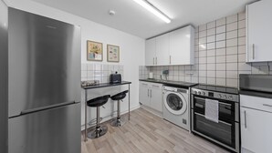Una cocina moderna con un refrigerador de acero inoxidable, lavadora, estufa y lavaplatos.