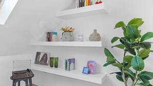 Una habitación con estantes blancos, un taburete pequeño y una planta.