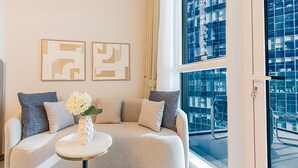 Un salon moderne avec un canapé aux lignes courbes, une petite table ronde ornée d’un vase et des œuvres d’art abstraites accrochées au mur.