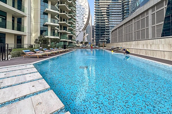 A swimming pool with lounge chairs and a person swimming.