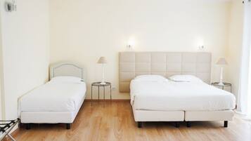 Una habitación de hotel con dos camas, suelo de madera y lámparas de noche.