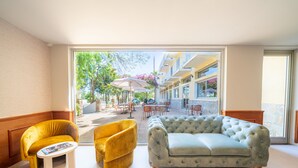A modern hotel lobby with a sofa, armchair, and a small table. - Hôtel Castellu (Lucciana)