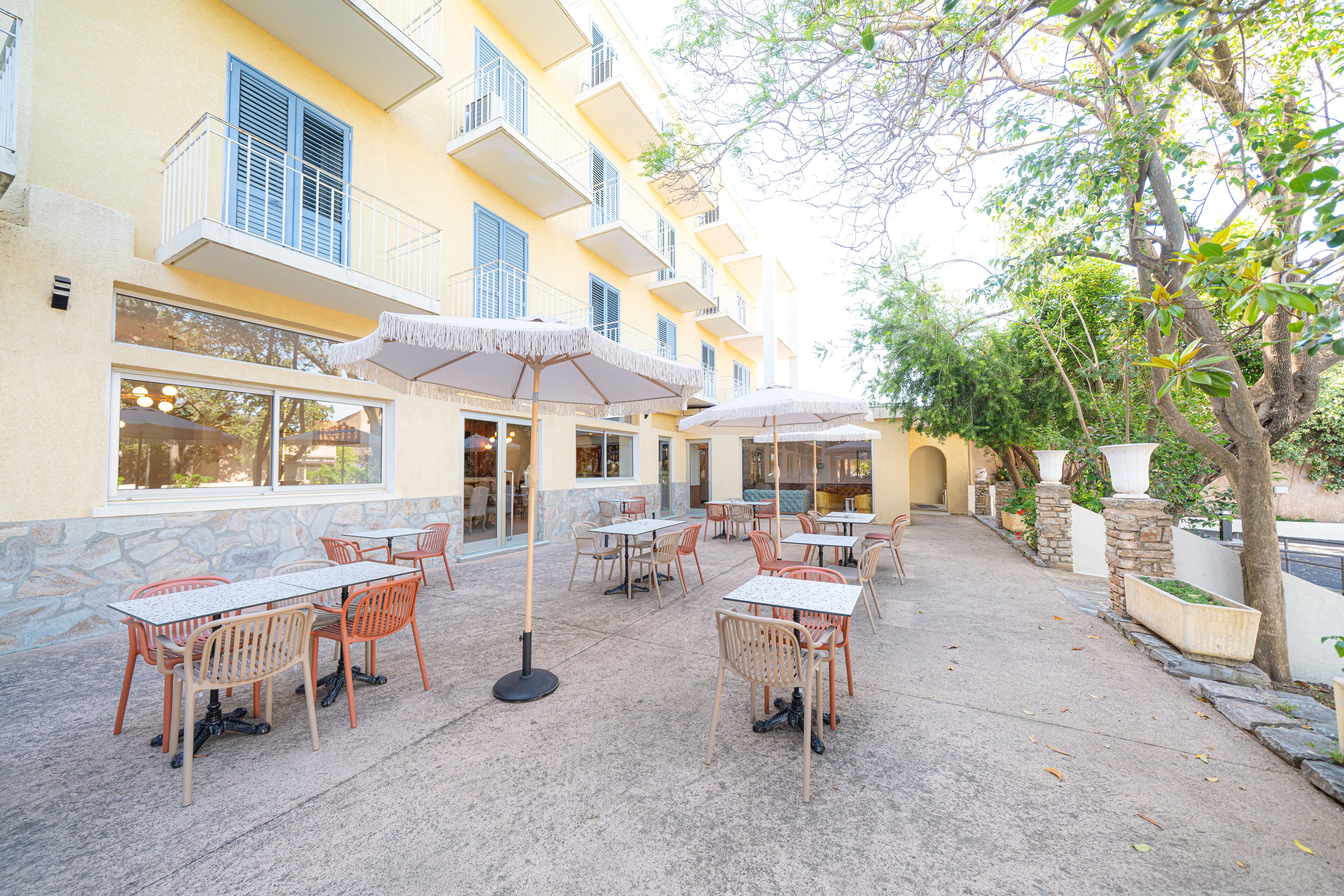 An outdoor patio area with tables and chairs, a stone wall, and a building with balconies.