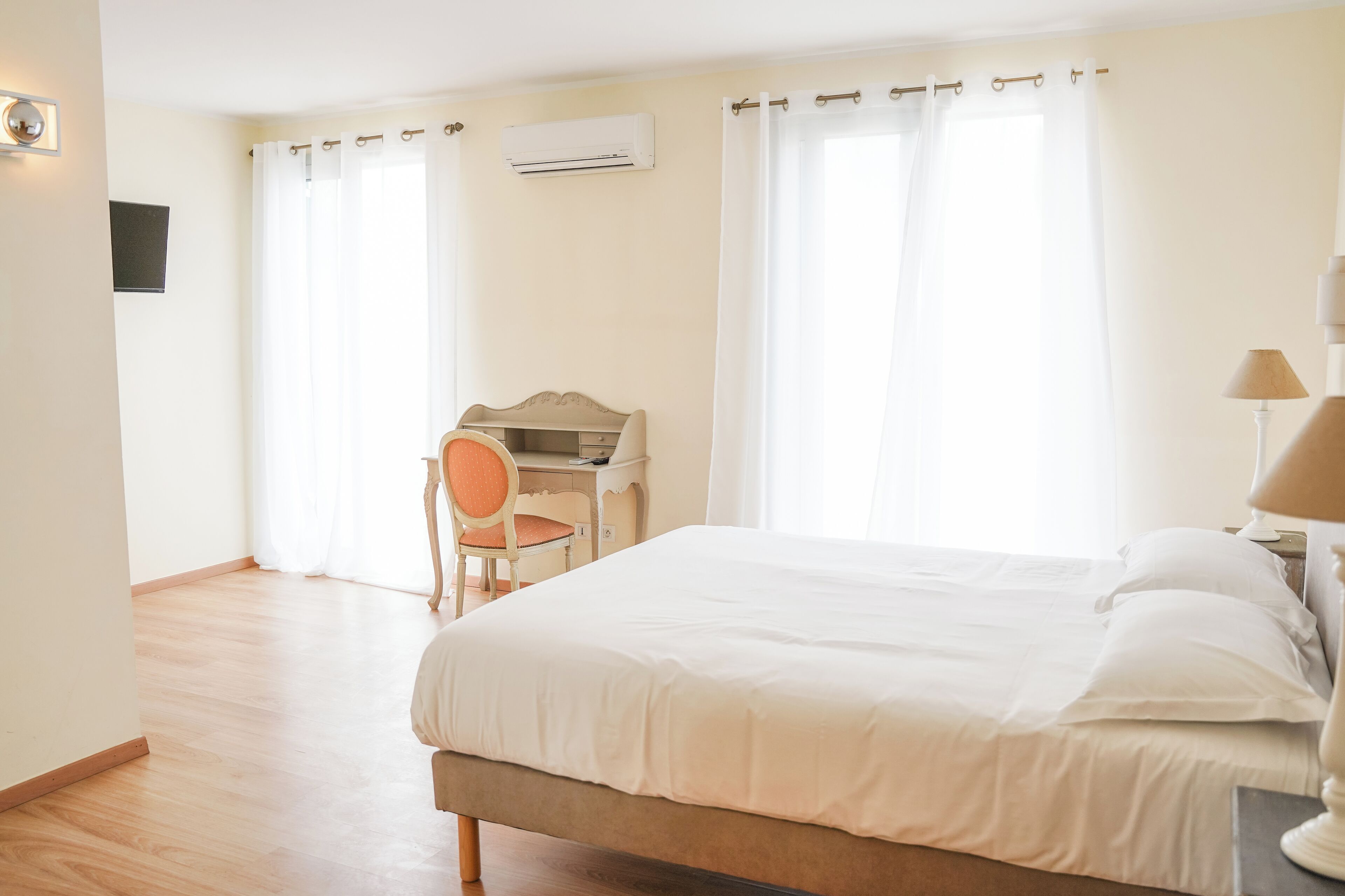 Une chambre d’hôtel avec un grand lit, un bureau avec une chaise et une lampe.