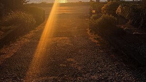 A sunset over a body of water with a pathway leading to the water's edge.